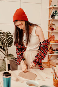 Woman wearing hat while standing by table