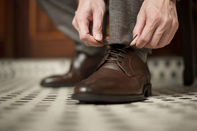 Low section of man tying shoelace at home