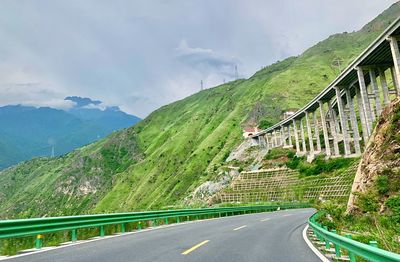 Road amidst green mountains against sky