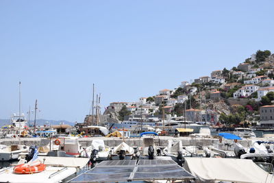 Sailboats in city against clear blue sky