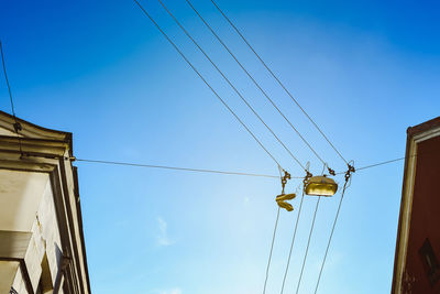 Low angle view of overhead cable cars against blue sky