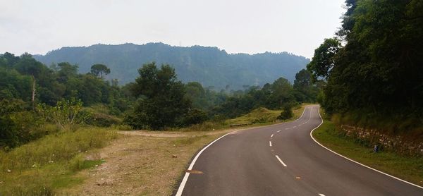 Road amidst trees against sky