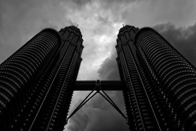 Low angle view of skyscrapers against cloudy sky