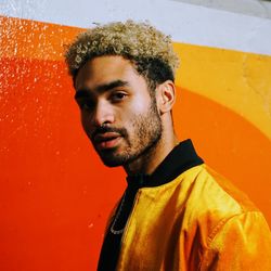 Portrait of young man looking away against orange wall