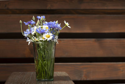 Bouquet of daisies and cornflowers in a glass vase on the tablel.