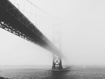 Low angle view of golden gate bridge over river during foggy weather
