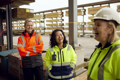 Happy multiracial female workers with colleague at industry
