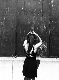 Rear view of woman standing against wall