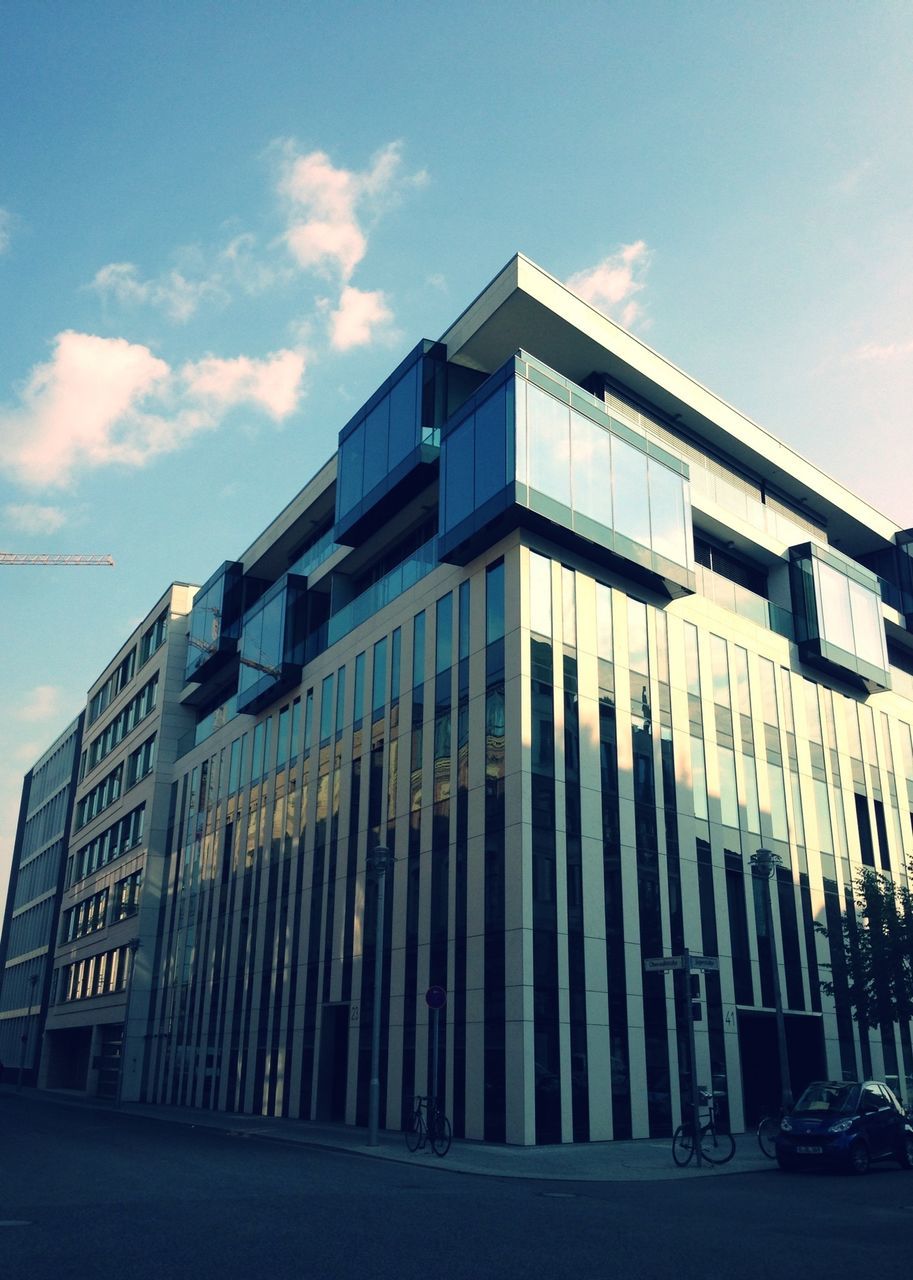 architecture, building exterior, built structure, sky, low angle view, city, building, street, in a row, cloud - sky, car, transportation, cloud, day, road, outdoors, blue, sunlight, land vehicle, window