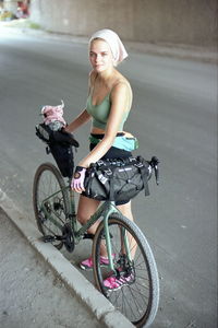 Portrait of woman with bicycle on road in city