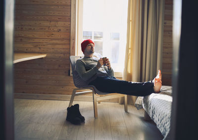 Side view of young woman using mobile phone while sitting at home