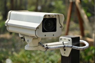 Close-up of security camera against trees