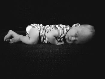 Portrait of young woman lying down against black background