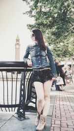 Full length portrait of young woman standing against tree