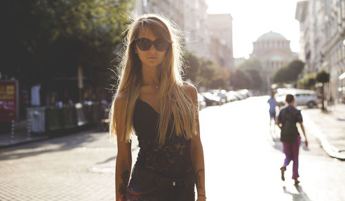 Portrait of young woman with arms raised standing in city