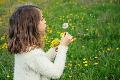 Side view of woman blowing bubbles while standing against plants