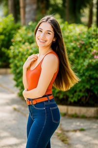 Portrait of young woman standing against trees