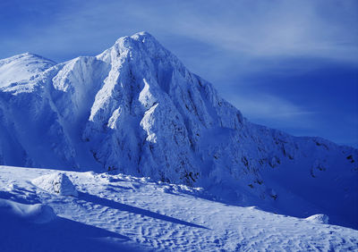 Scenic view of snowcapped mountains against blue sky