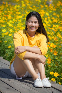 Portrait of smiling woman sitting on yellow flower