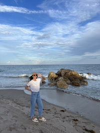 Full length of woman standing at beach against sky