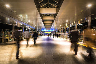 People walking on illuminated railroad station platform at night