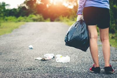 Low section of woman collecting garbage on road