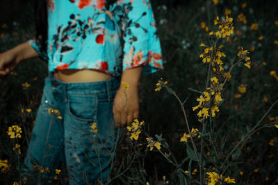 Midsection of woman standing by flowering plants