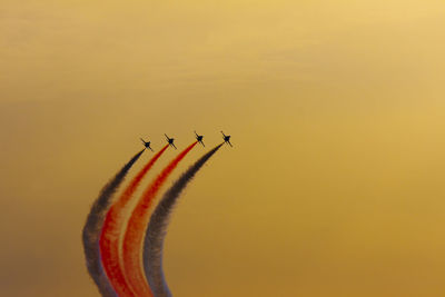 Low angle view of airplane flying against sky during sunset