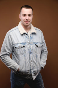 Portrait of young man standing against orange background