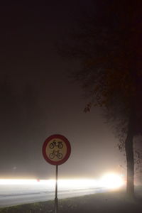 Road sign against sky at night