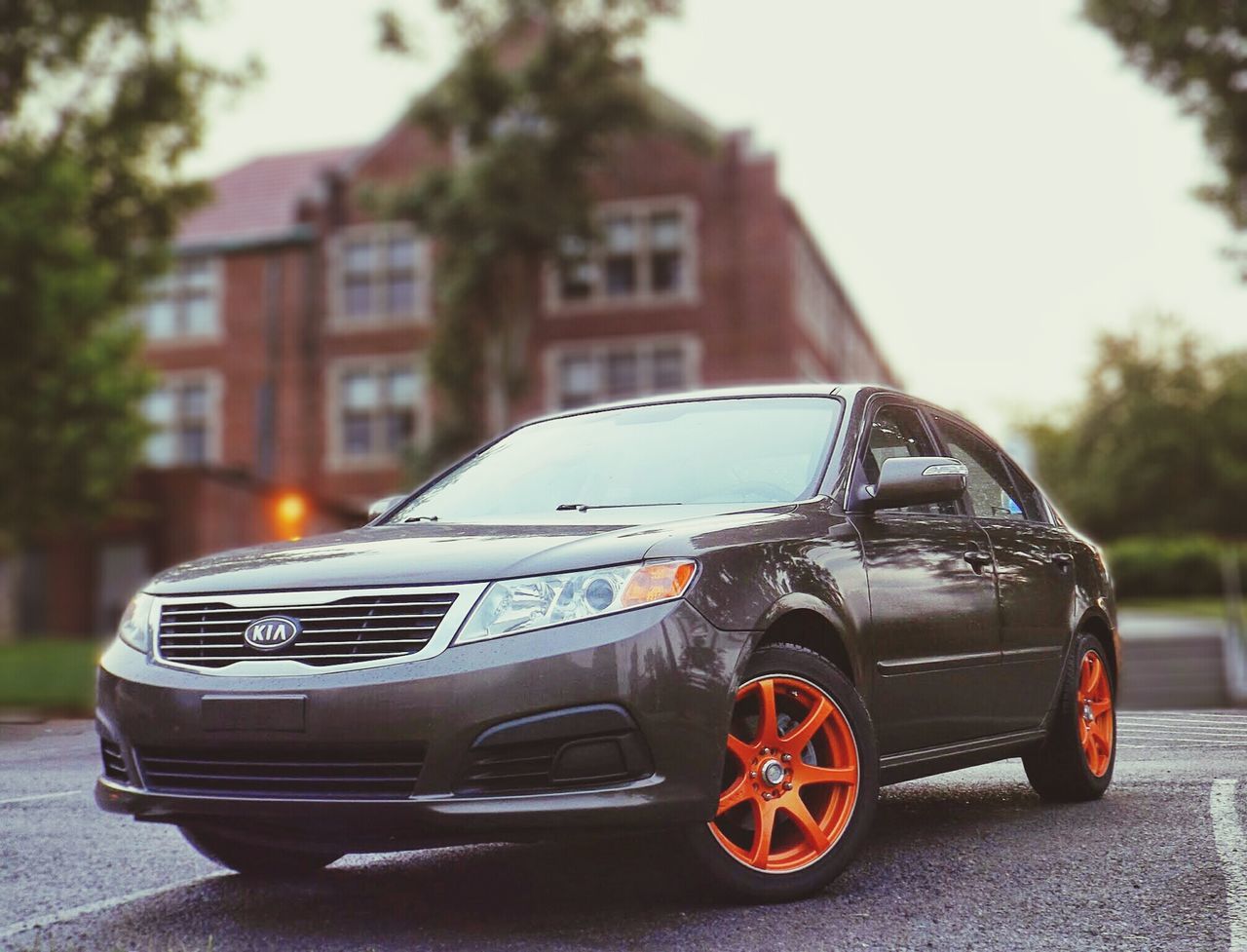 transportation, car, mode of transport, land vehicle, building exterior, street, tree, focus on foreground, architecture, built structure, stationary, outdoors, city, close-up, road, day, parking, travel, parked, no people