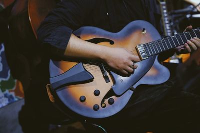 Midsection of man playing guitar