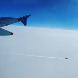 Low angle view of airplane flying against clear blue sky