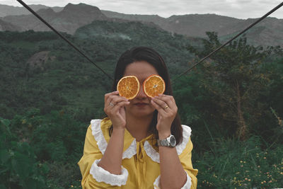 Portrait of man holding oranges against mountain