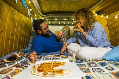 Couple enjoying pizza in illuminated room