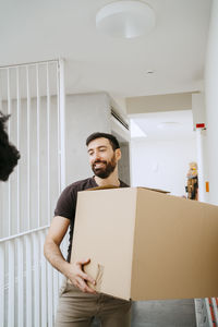 Smiling man holding cardboard box at new home