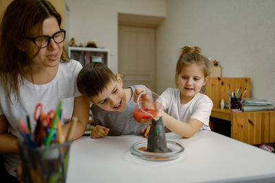 Mom and children at home are conducting an experiment with a volcanic eruption.