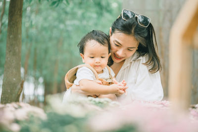 Mother and son standing by flowering plants