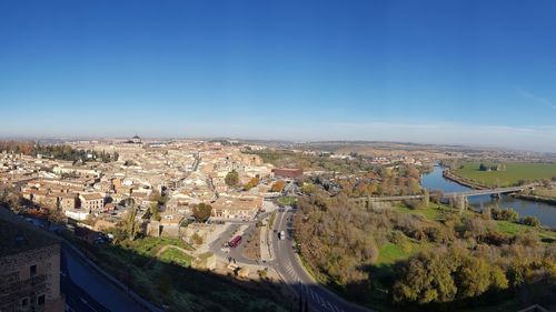 High angle view of river amidst buildings against clear blue sky