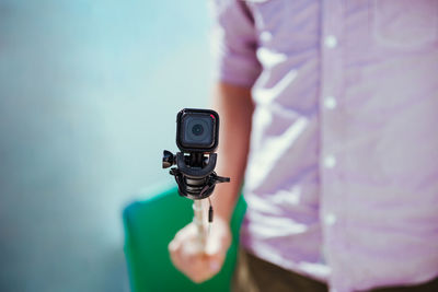 Midsection of man holding wearable camera