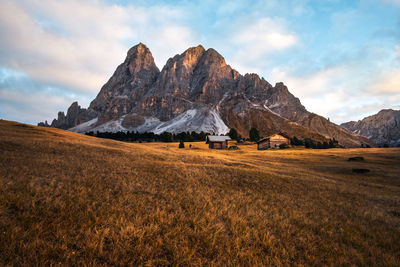 Scenic view of landscape against cloudy sky during sunset