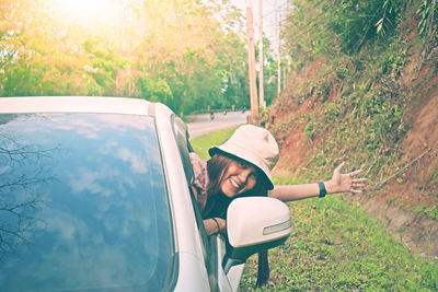 Portrait of happy woman leaning out from car window