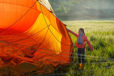 Full length of girl preparing tent on field at campsite