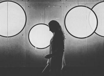 Side view of woman standing against window