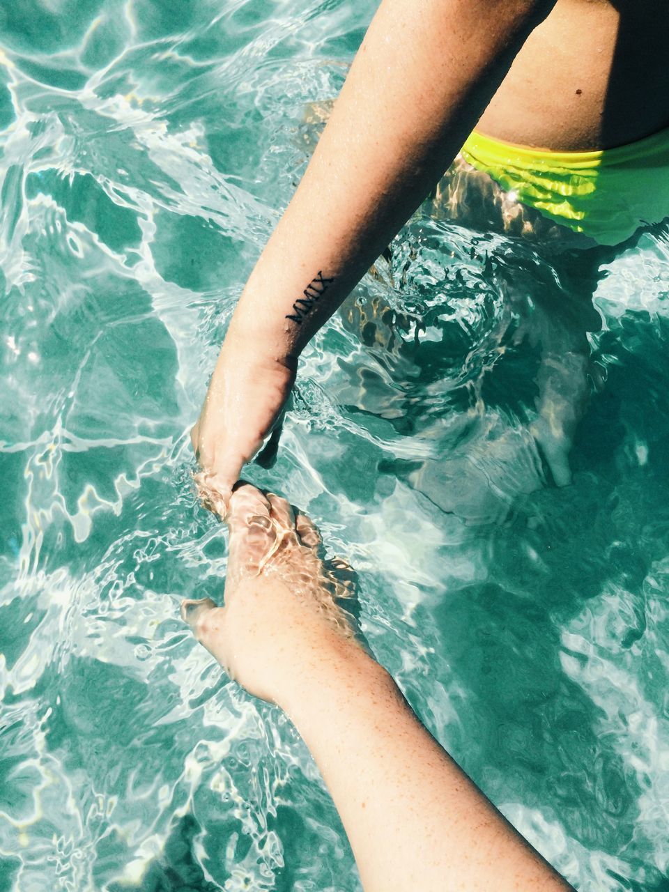 LOW SECTION OF WOMAN STANDING ON SWIMMING POOL