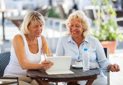 Smiling senior female friends looking in digital tablet on table