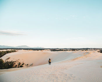 Rear view of man walking on beach against sky