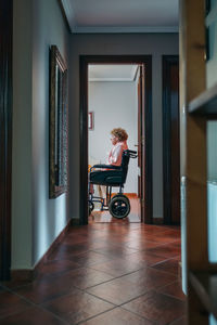 Woman sitting on wheelchair at home