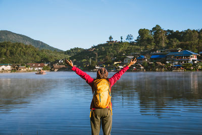 Man standing in front of lake against sky