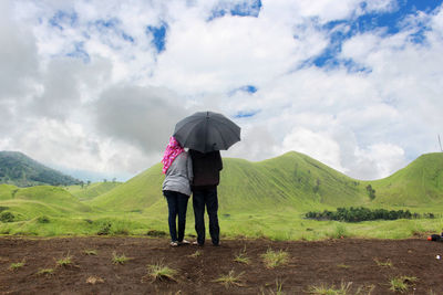 Rear view of couple standing on field against sky